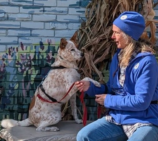 Kathleen and Atha facing each other on a bench, with Atha’s paw resting in Kathleen’s hand.